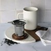 Tasse blanche Kyoseitea en mise en scène avec infuseur